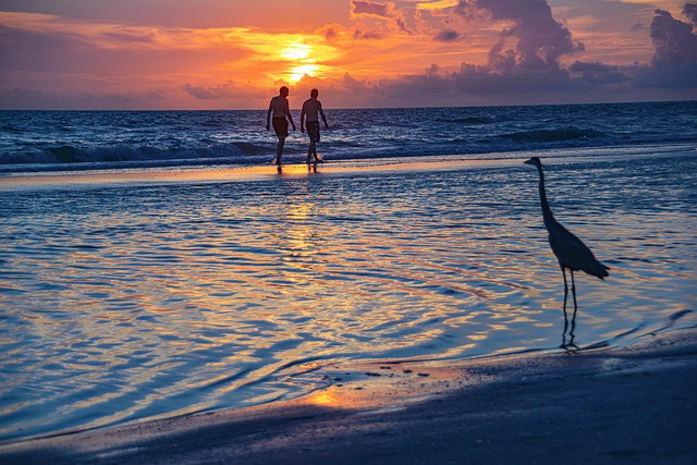 People strolling on the beach with the sunset over the ocean in the background.