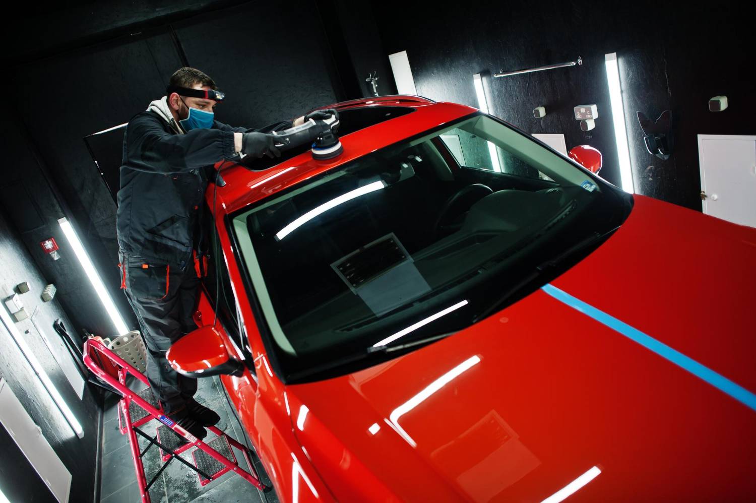 car-detailing-concept-man-face-mask-with-orbital-polisher-repair-shop-polishing-roof-orange-suv-car